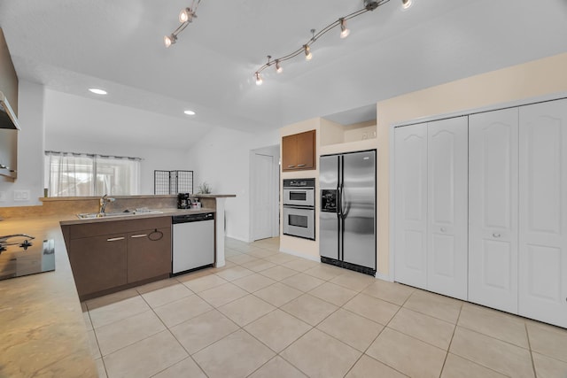 kitchen with light tile patterned floors, appliances with stainless steel finishes, a peninsula, light countertops, and a sink