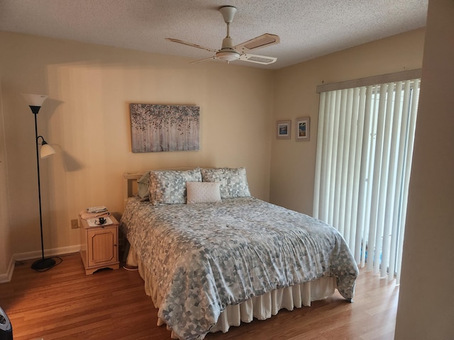 bedroom featuring a textured ceiling, multiple windows, wood finished floors, and a ceiling fan