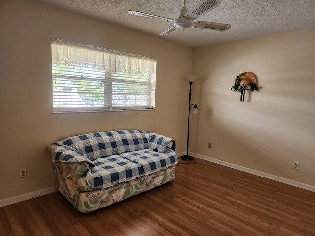 sitting room with a textured ceiling, wood finished floors, a ceiling fan, and baseboards