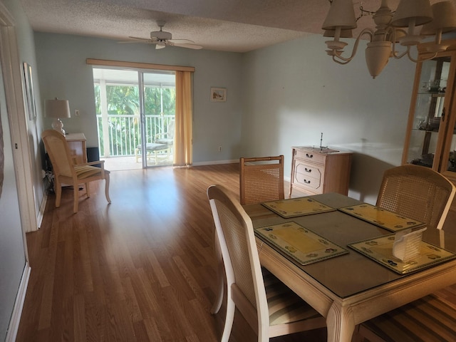 dining area with a textured ceiling, baseboards, wood finished floors, and ceiling fan with notable chandelier