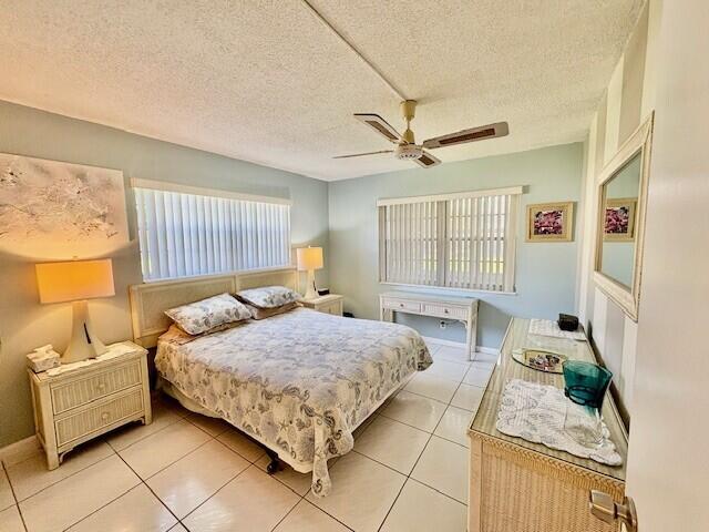 bedroom with ceiling fan, multiple windows, a textured ceiling, and light tile patterned flooring