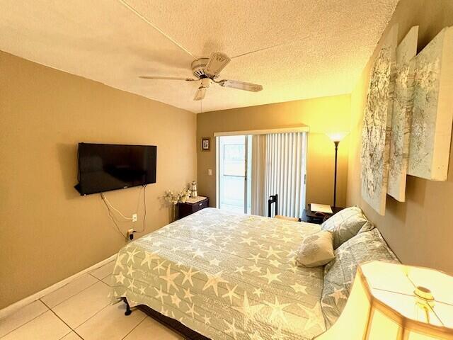 bedroom featuring baseboards, a textured ceiling, ceiling fan, and tile patterned flooring