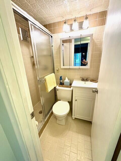 full bathroom with vanity, tile patterned flooring, a shower stall, tile walls, and toilet