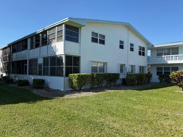 view of side of property featuring a lawn and stucco siding