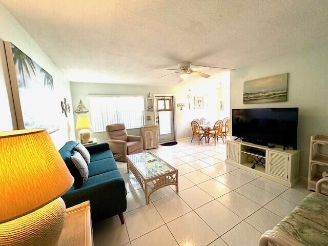 living room with tile patterned floors, a textured ceiling, and a ceiling fan