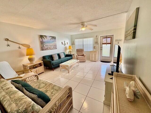 living area featuring light tile patterned floors, a textured ceiling, and a ceiling fan