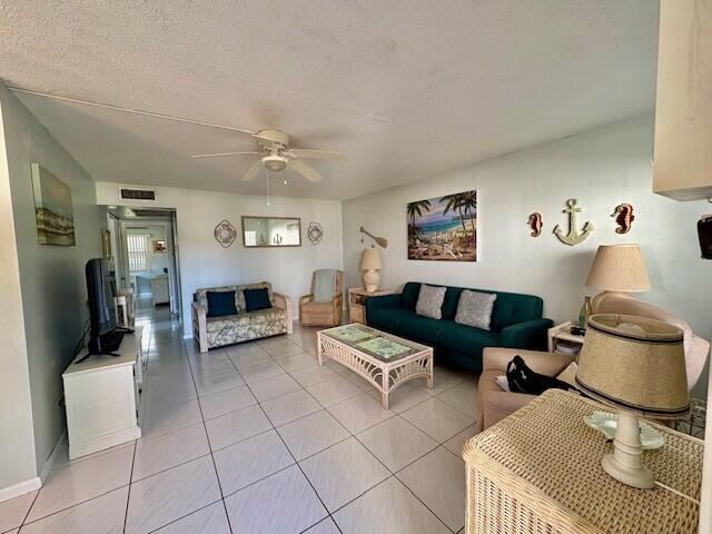 living area featuring visible vents, a textured ceiling, ceiling fan, and light tile patterned flooring