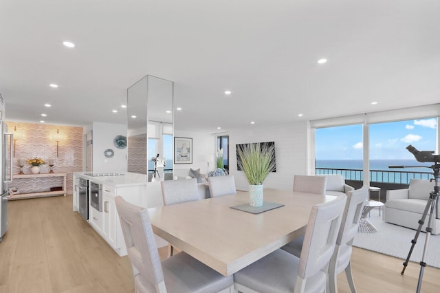 dining space with light wood finished floors, a water view, and recessed lighting