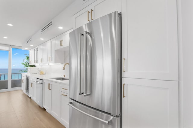 kitchen with appliances with stainless steel finishes, white cabinets, a sink, and light countertops