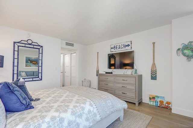 bedroom with light wood-type flooring, visible vents, and baseboards