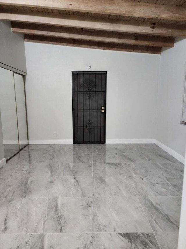 interior space featuring beam ceiling and baseboards