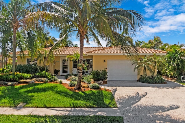 mediterranean / spanish house featuring stucco siding, an attached garage, driveway, and a front lawn