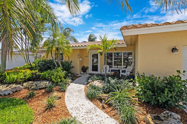 view of exterior entry featuring a tiled roof and stucco siding