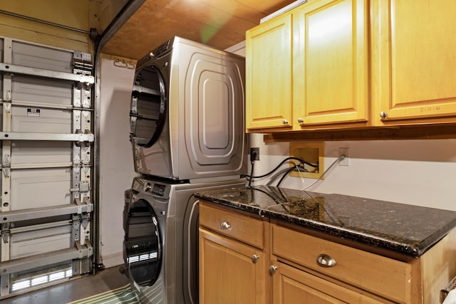 laundry room featuring cabinet space, a garage, and stacked washer and dryer