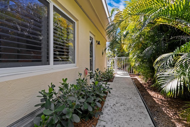 view of property exterior with stucco siding and a gate