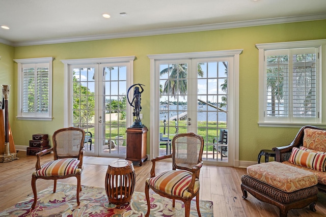living area featuring baseboards, french doors, light wood-type flooring, and crown molding