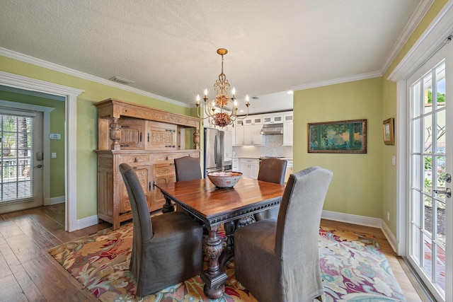 dining space with light wood finished floors, visible vents, an inviting chandelier, ornamental molding, and baseboards