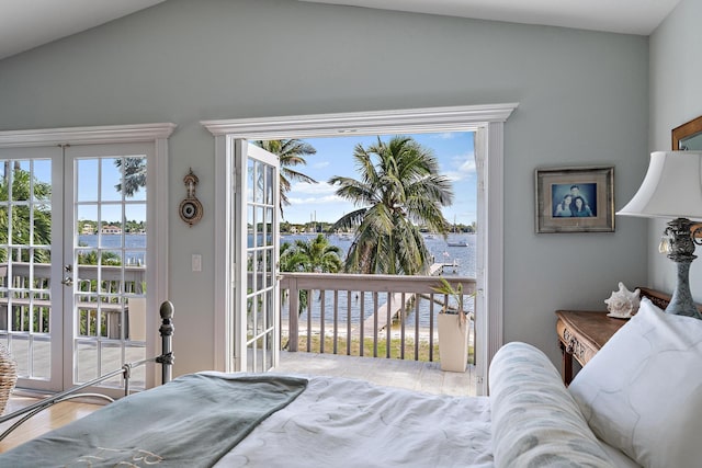 bedroom featuring french doors, lofted ceiling, a water view, wood finished floors, and access to outside