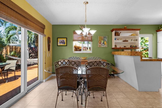 dining area with light tile patterned floors, a textured ceiling, and a notable chandelier