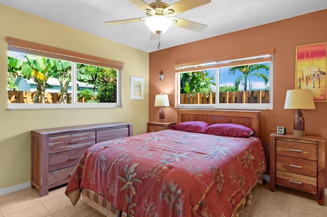 bedroom with light tile patterned floors, multiple windows, baseboards, and a textured ceiling