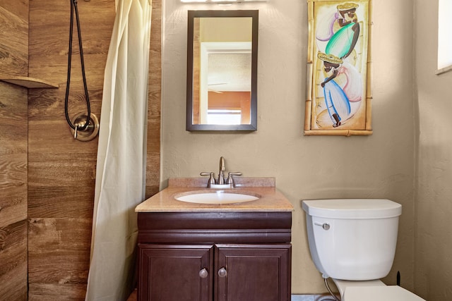 bathroom with tiled shower, vanity, and toilet