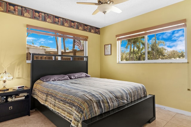 bedroom featuring light tile patterned floors, a textured ceiling, a ceiling fan, and baseboards