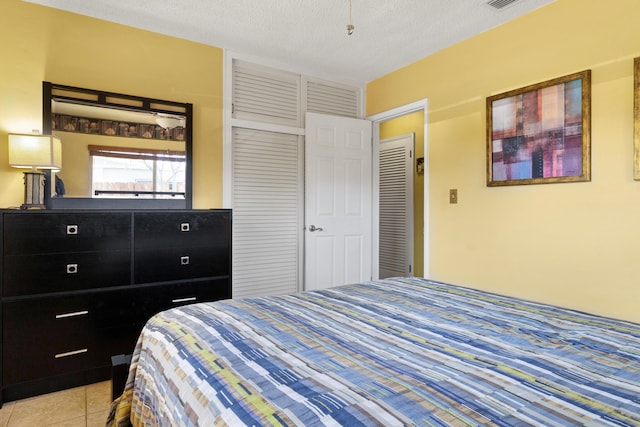 bedroom with light tile patterned floors, visible vents, and a textured ceiling