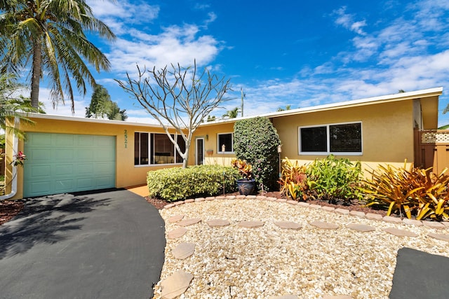 ranch-style house with a garage, aphalt driveway, and stucco siding