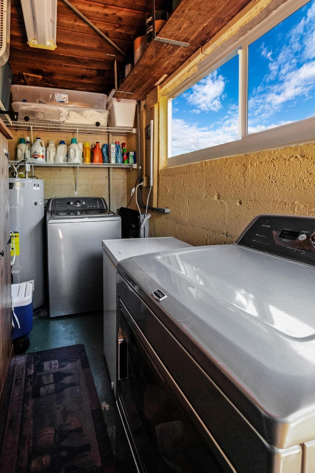 clothes washing area with laundry area, water heater, and independent washer and dryer