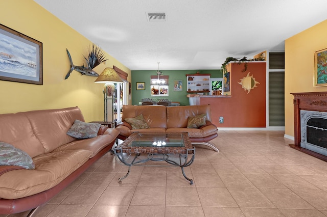 tiled living area featuring visible vents, an inviting chandelier, and a premium fireplace