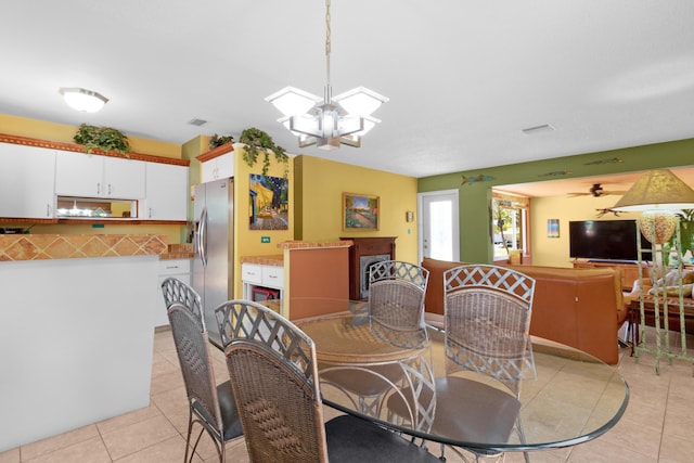 dining room featuring light tile patterned floors, ceiling fan with notable chandelier, and visible vents