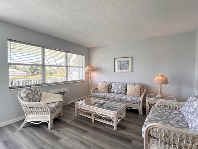 living area with a textured ceiling, a wall mounted air conditioner, wood finished floors, and baseboards