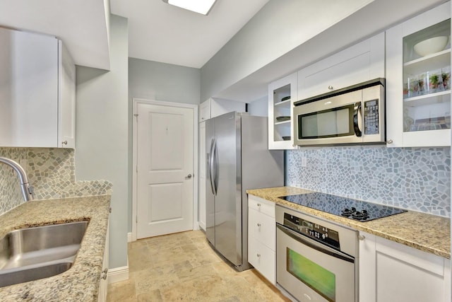 kitchen with stainless steel appliances, white cabinetry, a sink, and light stone counters