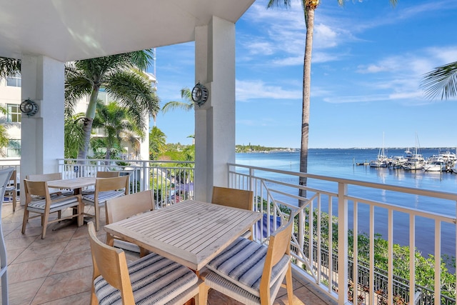 balcony with outdoor dining space and a water view