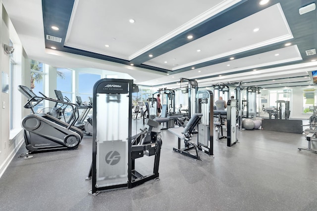 exercise room featuring plenty of natural light, ornamental molding, and a raised ceiling