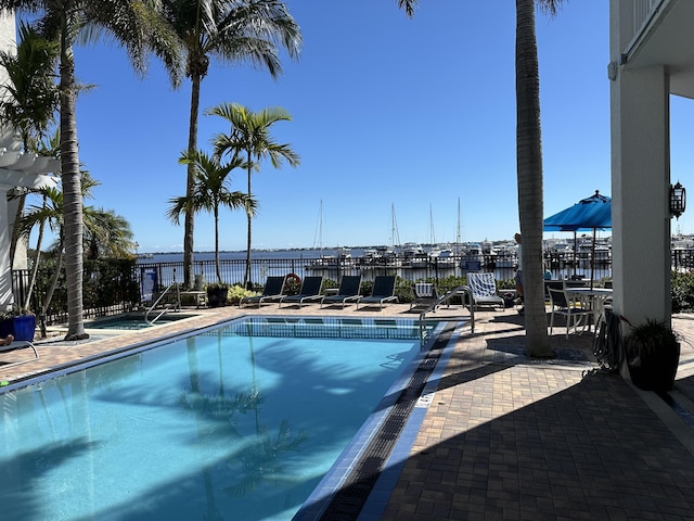 community pool featuring a patio area, fence, and a water view