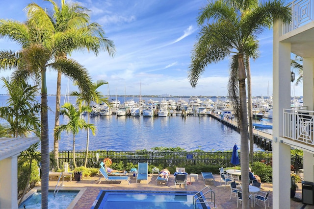 pool with a water view, fence, and a patio