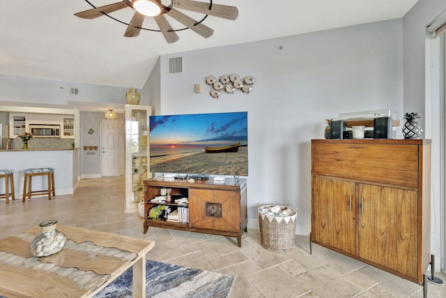 living area featuring lofted ceiling, ceiling fan, stone finish floor, and visible vents