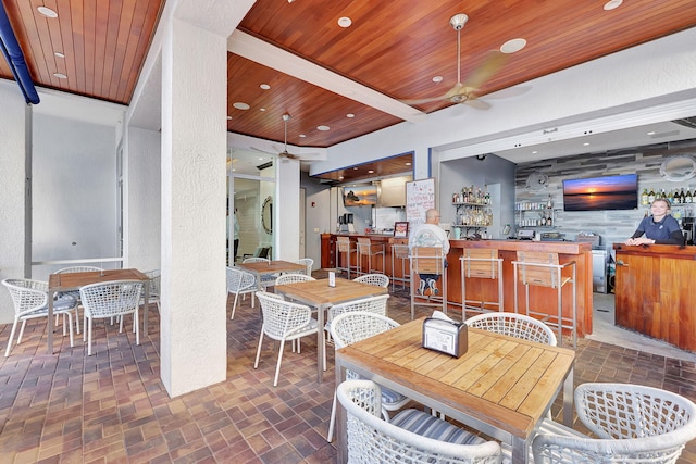 dining area with brick floor, wooden ceiling, recessed lighting, a ceiling fan, and indoor wet bar