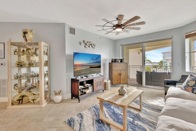 living area with baseboards, visible vents, stone tile flooring, and a ceiling fan