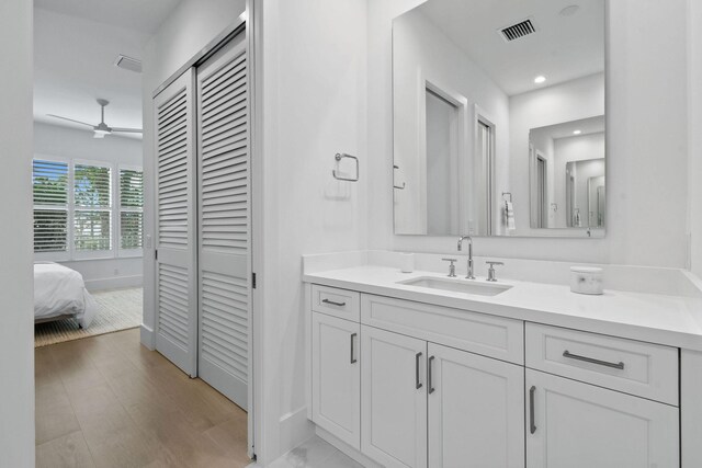 bathroom with a closet, visible vents, vanity, and wood finished floors