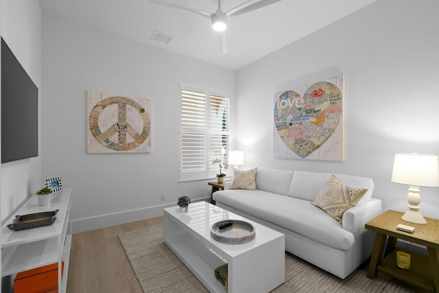 living area featuring wood finished floors, a ceiling fan, and baseboards