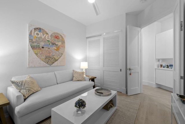 living area featuring light wood-style flooring and a ceiling fan