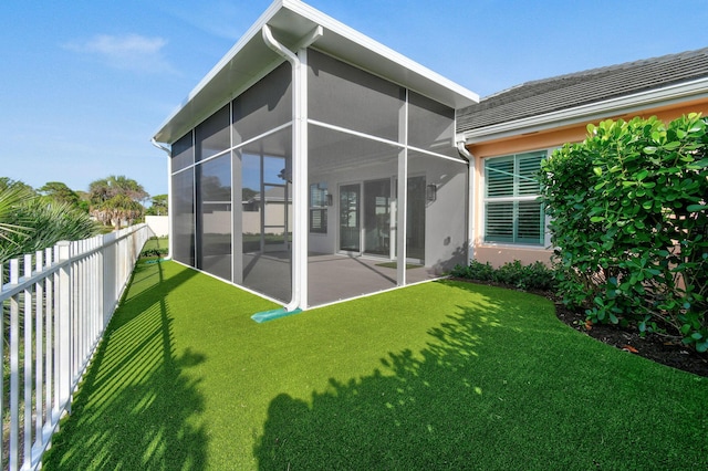 rear view of house with a sunroom, a fenced backyard, a yard, and stucco siding