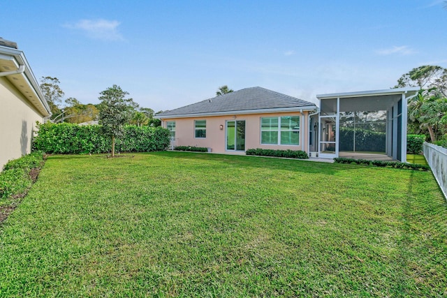 rear view of property with a sunroom, stucco siding, fence, and a lawn