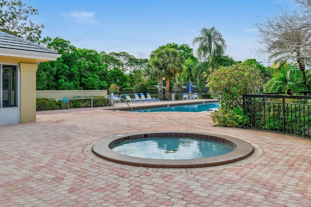 community pool featuring fence, a community hot tub, and a patio