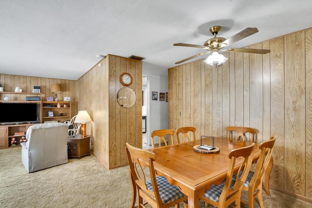 dining space with carpet floors, ceiling fan, wooden walls, and visible vents