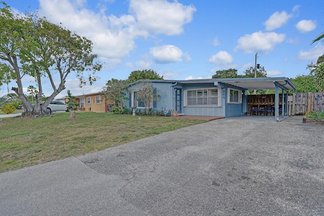 view of front of home featuring aphalt driveway, fence, a front lawn, and an attached carport