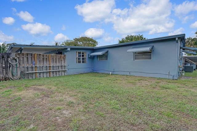 back of house featuring central AC, a lawn, and fence