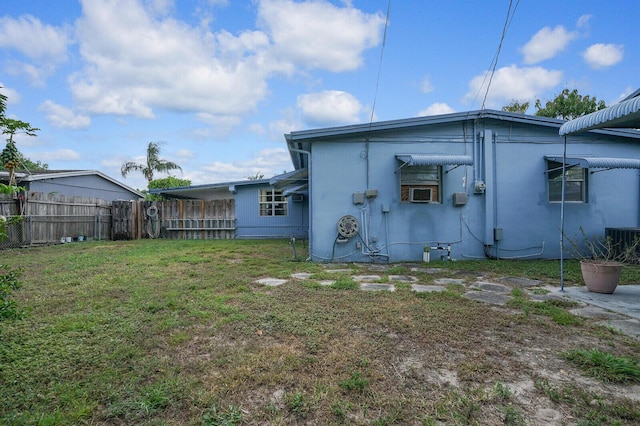 back of property with central AC unit, a lawn, and fence